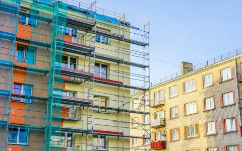 Budynek w remoncie, rusztowania i siatka ochronna. Balkony we wspólnocie mieszkaniowej czekają na odnowienie.