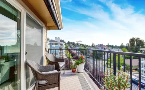 Wygodny balkon z rattanowymi meblami i kwiatami. Inspiracje na płytki na balkon.