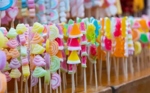 Coloridas manualidades con chuches en palitos, formando un arcoíris de dulces.