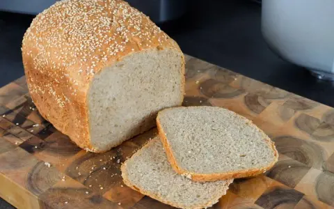 Frisch gebackenes sesam brot, mit zwei Scheiben auf einem Holzbrett.