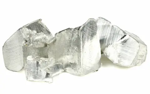 Pezzi grezzi di stagno, un metallo argenteo con una superficie graffiata, che ricordano rocce o cristalli irregolari.