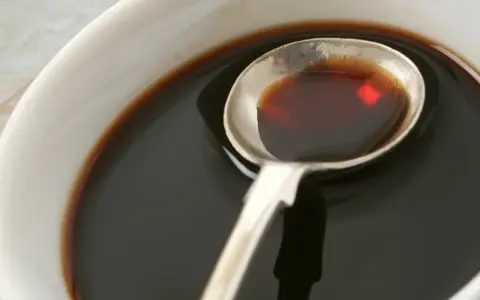 Łyżka z ciemnym płynem, idealnym do sosów i dressingów. Inspiracja do ocet balsamiczny przepisy.