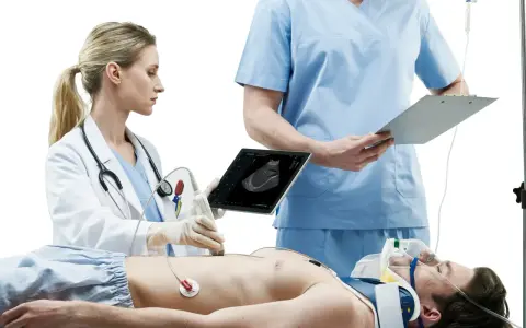 Lekarka wykonuje USG pacjenta, który leży na stole. Obok stoi lekarz z notatkami. Szybka diagnostyka to klucz do ratowania życia.