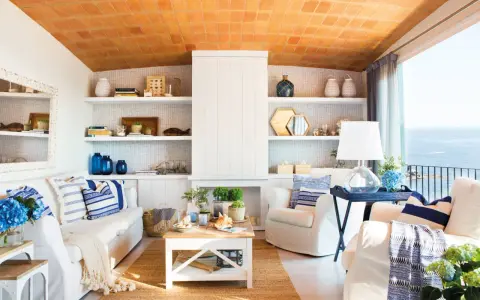 Salón con vistas al mar, decoración náutica y techo de tejas. Un espacio que evoca la sensación de estar en la playa en casa.