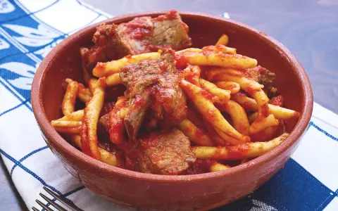 Piatto di pasta fresca con ragù di carne, un sapore autentico del cibo tipico calabrese in una ciotola di terracotta.