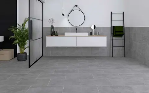 Modernes Badezimmer mit grauen Bodenfliesen und Wandfliesen, die das Ambiente von fliesen sanieren unterstreichen. Ein schwebendes Waschbecken und eine Glasdusche runden das Bild ab.