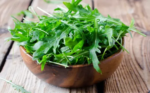 Frischer Rucola in einer Holzschale, bereit für einen gesunden Salat.