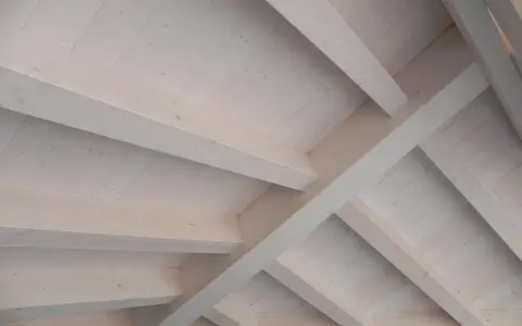 Techo de madera con vigas y tablones, acabado con veladura blanca que resalta la veta natural.