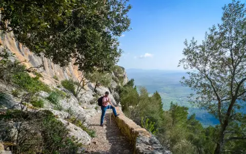 Mann mit Wanderstock und Rucksack genießt die Aussicht auf Mallorca. Ein toller Tag zum Wandern auf Mallorca!