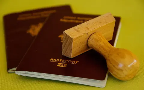 Drewniany stempel nad paszportem, gotowy do pieczętowania. Marzysz o podróży? Biuro paszportowe Lublin pomoże Ci spełnić marzenia.