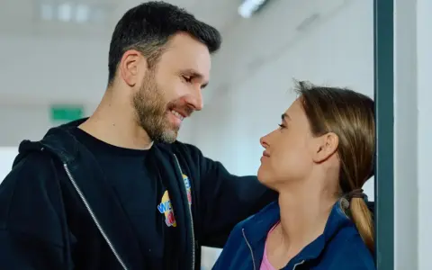 Uśmiechnięty mężczyzna patrzy na kobietę, która opiera się o ścianę. Może rozmawiają o tym, jak czytać mangę.