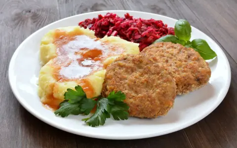 Dwa soczyste mielone z piekarnika, podane z purée ziemniaczanym polanym sosem, surówką z buraków i listkami bazylii.