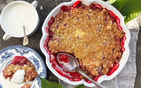 En härlig hallonpaj smulpaj med krispig topping, serverad med vaniljsås. Perfekt sommarfika!
