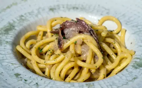 Un piatto di spaghetti con acciughe e prezzemolo, un'ottima idea per scoprire cosa mangiare a Padova.