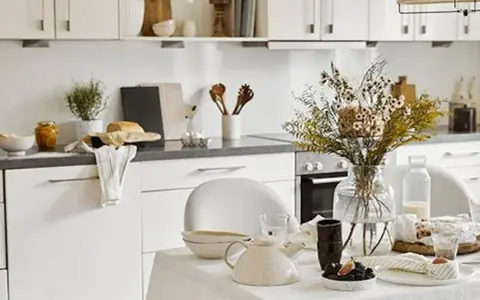 Cuisine lumineuse dans une maison style cottage anglais, avec vaisselle et bouquet de fleurs séchées sur la table.