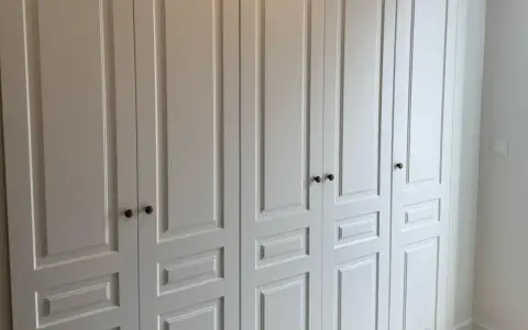 Armario empotrado blanco con puertas de paneles y tiradores oscuros. Perfecto para forrar armario empotrado y dar un toque elegante.