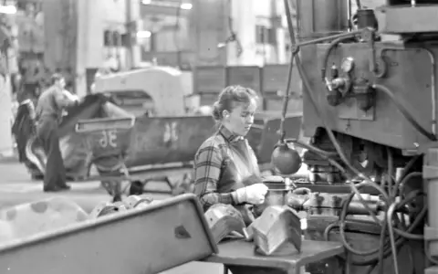 Kvinna arbetar vid maskin i fabriken, en del av arbetskraftsinvandring Sverige 1960.