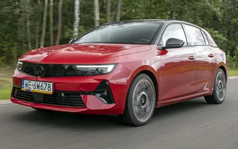 Czerwony Opel Astra Turbo pędzi leśną drogą.