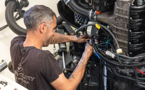 Un mécanicien s'affaire sur un moteur électrique, câbles et tuyaux visibles. Il sait comment tester un moteur électrique pour assurer son bon fonctionnement.