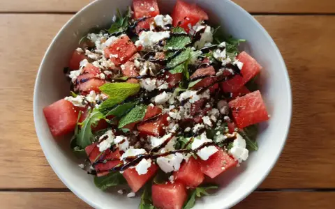 En uppfriskande sallad med tärnad vattenmelon, smulad fetaost och färsk basilika, ringlad med balsamvinäger.