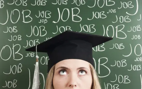 Absolventin mit Doktortitel blickt nach oben, während die Tafel voller "JOB" steht. Die Suche nach Arbeit nach dem Studium ist intensiv.