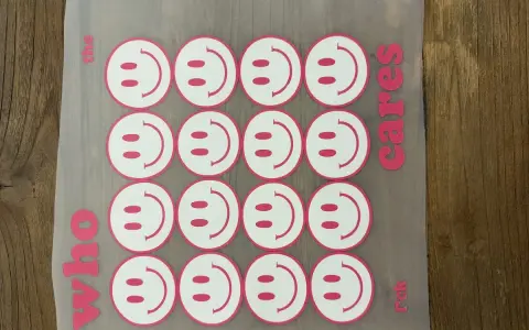Aufkleber mit Smiley-Gesichtern, bereit für das Textildruck-Verfahren. "Who the cares rck" steht auf dem Transferpapier.