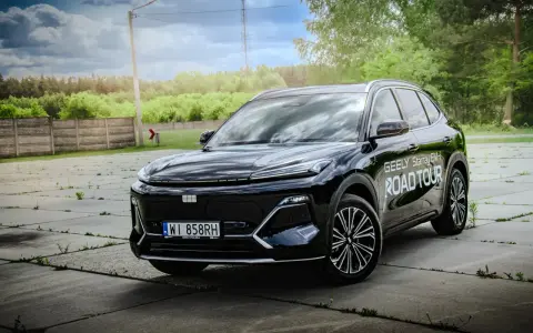 Czarny Geely Starray EM-i gotowy na Road Tour, lśniąc na tle zieleni i chmur.