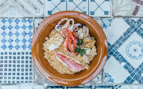 Un saporito cous cous di pesce con gamberi, calamari, cozze e triglia, guarnito con prezzemolo fresco.