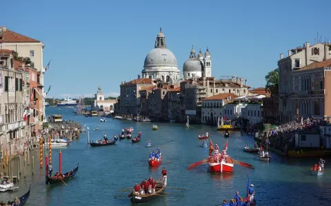 La Regata Storica anime le eaux de Venise, avec des gondoles et des bateaux traditionnels en compétition, sous le regard de la basilique Santa Maria della Salute.