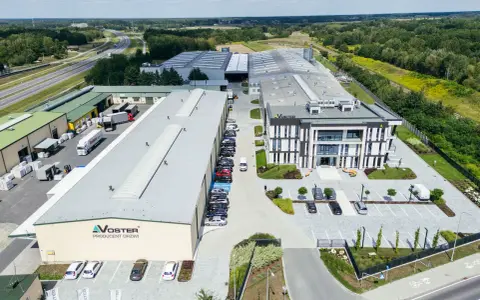 Nowoczesny kompleks produkcyjny Voster producent drzwi, z drogą szybkiego ruchu w tle.