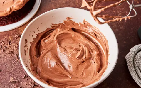 Schokocreme mit Puddingpulver, cremig und glatt, bereit für einen köstlichen Kuchen. Ein Handmixer mit Schokoladenresten liegt daneben.