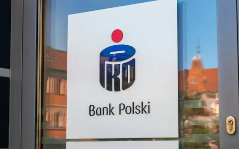 Logo PKO Bank Polski na drzwiach. W tle odbicie kamienicy.