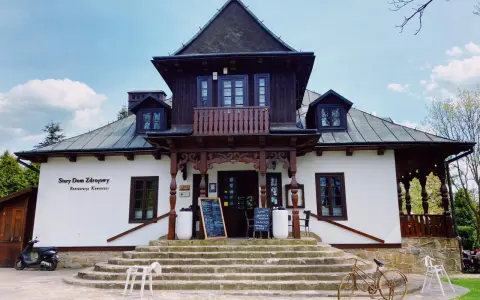 Stary Dom Zdrojowy w Beskidach, z charakterystyczną architekturą i kamiennymi schodami, zaprasza do restauracji.