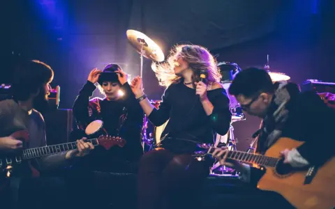 Band bei der Probe, die eine **cover musik** spielt. Sängerin mit Mikrofon, Gitarristen und Schlagzeuger im Scheinwerferlicht.