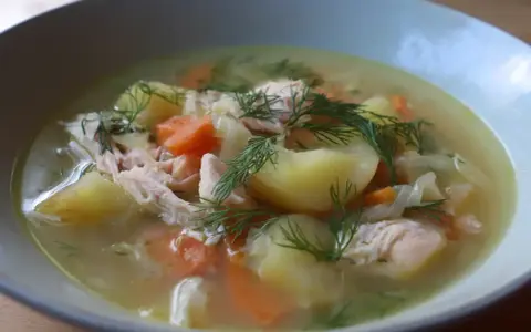 En närbild av en skål med värmande fisksoppa, full av potatis, morötter och dill. Ett perfekt fisksoppa recept för en kall dag.