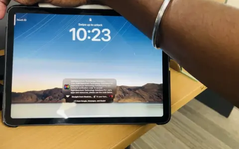Tablet z włączonym ekranem blokady, widoczny napis "Touch ID" i godzina 10:23. Na ekranie wyświetla się powiadomienie z kodem weryfikacyjnym.