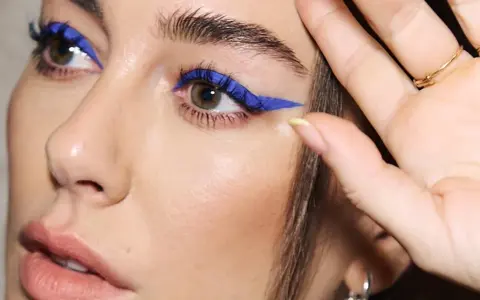 Ojos azules y piel blanca realzados con un audaz delineado azul eléctrico.