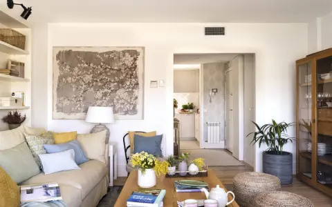 Ideas para decorar un salón moderno y elegante: sofá beige, mesa de centro de madera, arte floral, plantas y detalles acogedores.