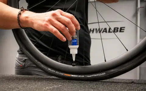 Eine Hand gibt Dichtmilch in den Fahrradschlauch eines Schwalbe Reifens.