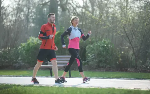 Ein Mann und eine Frau machen zügig **power walking** im Park.