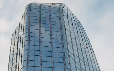Trabajadores en altura limpian ventanas de edificio moderno. Sikaflex para que sirve: sellar y unir, asegurando la integridad de estas estructuras.
