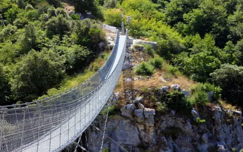 Un lungo ponte tibetano si snoda tra rocce e vegetazione lussureggiante, offrendo un'avventura mozzafiato nei dintorni di Salerno.
