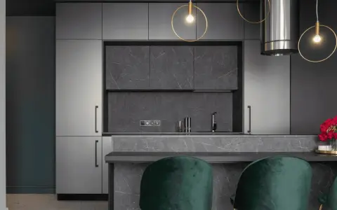 Cuisine moderne avec armoires grises, îlot en marbre et suspensions dorées. Pour un éclairage optimal, combien de lumen pour une cuisine ?