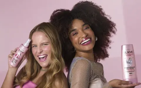 Dos mujeres sonríen, una con pelo liso y otra con pelo esponja, ambas sostienen productos Elseve para un brillo espectacular.
