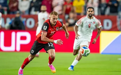 Jugadores de fútbol en acción. El número 15 de Austria corre con el balón, mientras otro jugador se acerca. ¿Quién juega hoy?