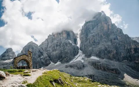 Kleine Kapelle vor imposanten Felsriesen in den Alpen. Ein perfekter Ort für mehrtageswanderungen in Europa.