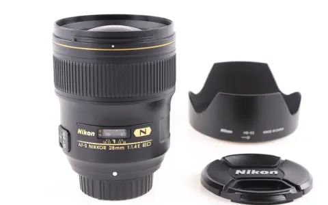 Obiektyw AF-S NIKKOR 28mm 1:1.4E ED z osłoną przeciwsłoneczną i deklem. Jasne oznaczenia obiektywów Nikon.