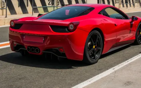 Czerwone Ferrari 458 Italia na torze wyścigowym, widok z tyłu.