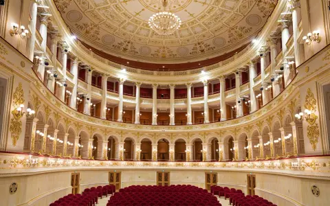 Interni sfarzosi del teatro Amintore Galli, con poltrone rosse e decorazioni dorate. Scopri i prossimi eventi!