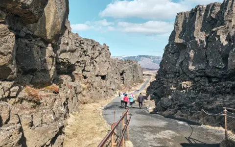 Spacerem przez szczelinę tektoniczną w parku narodowym Þingvellir. Grupa turystów podziwia surowe piękno islandzkiej przyrody.